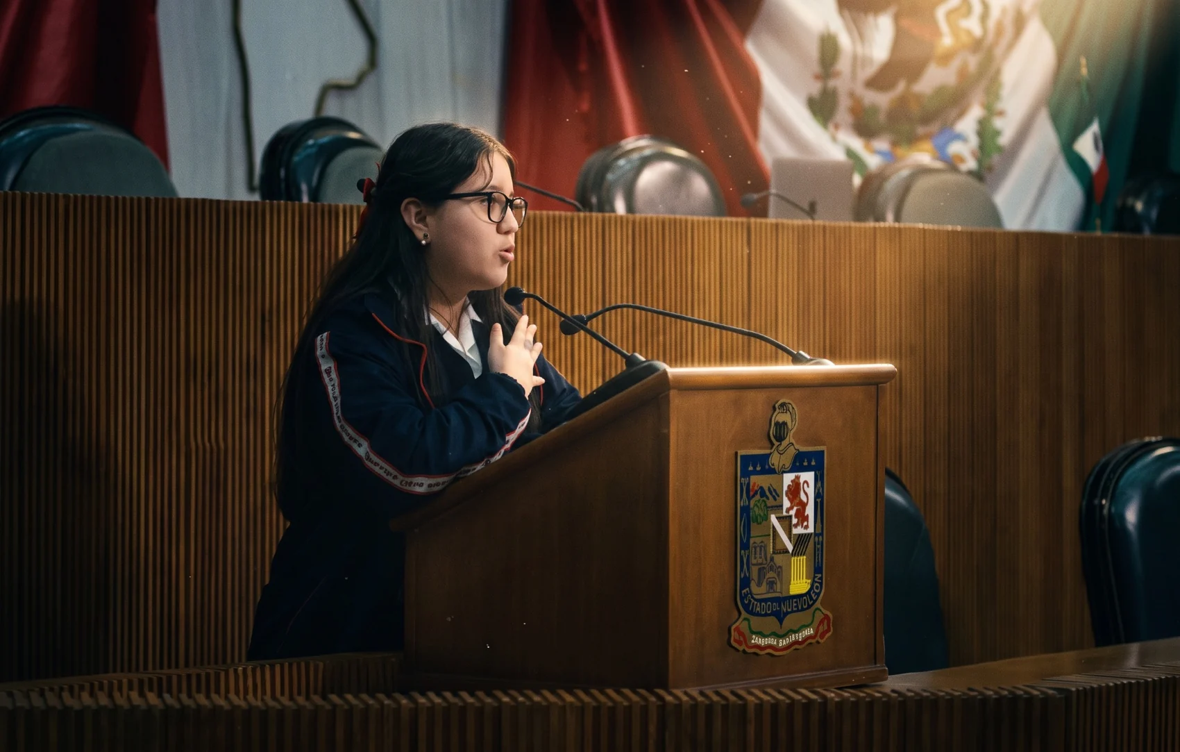 Gabriela hablando ante un micrófono en la tribuna del Congreso del Estado de Nuevo León